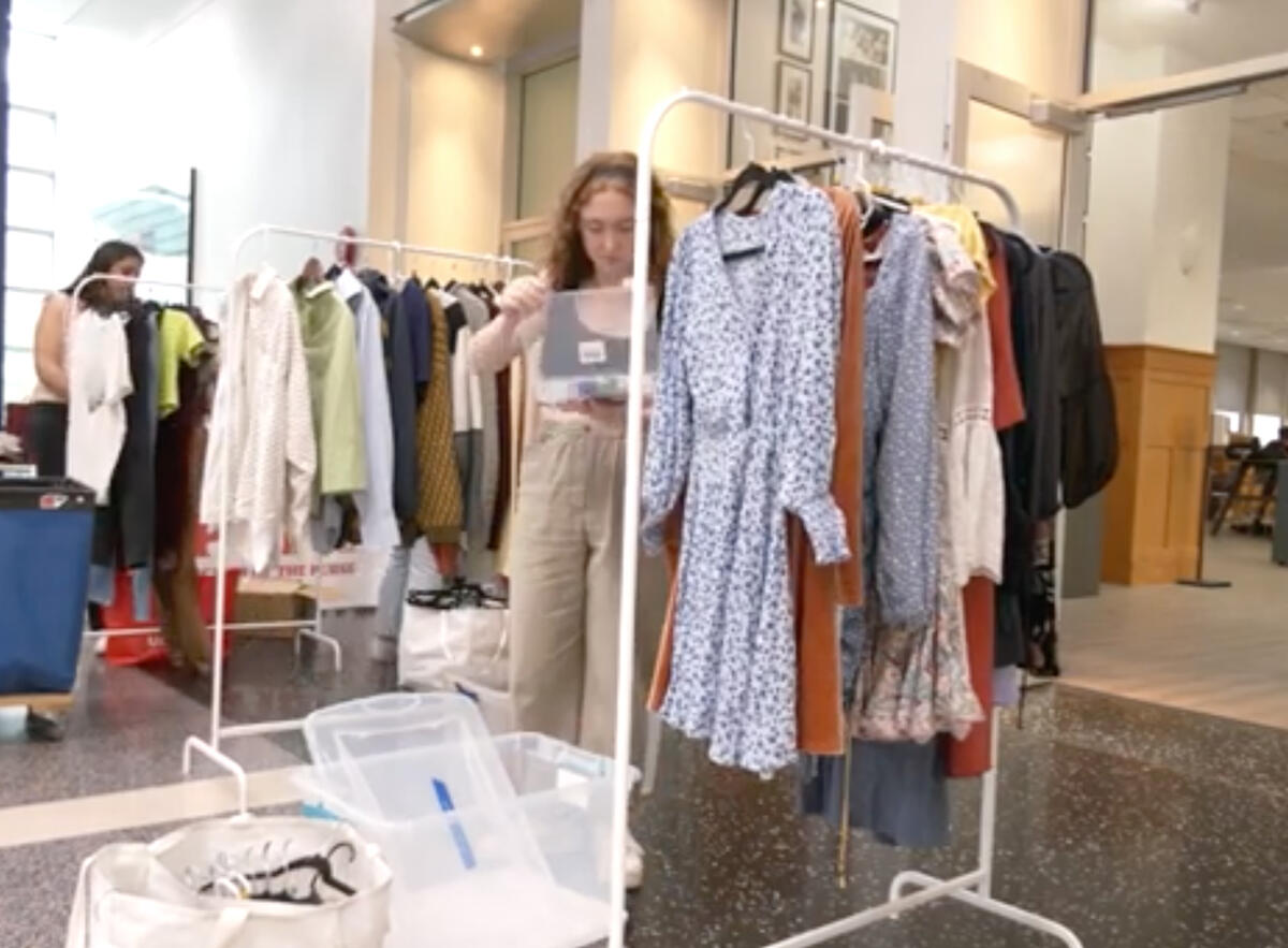 Pop! Thrift co-founder Maya Levine setting up a clothing rack at a pop-up store